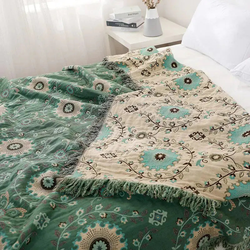 Cotton Sofa Throw Blanket by Zendrop spread across a bed, illustrating the vibrant green and cream design with decorative floral motifs.