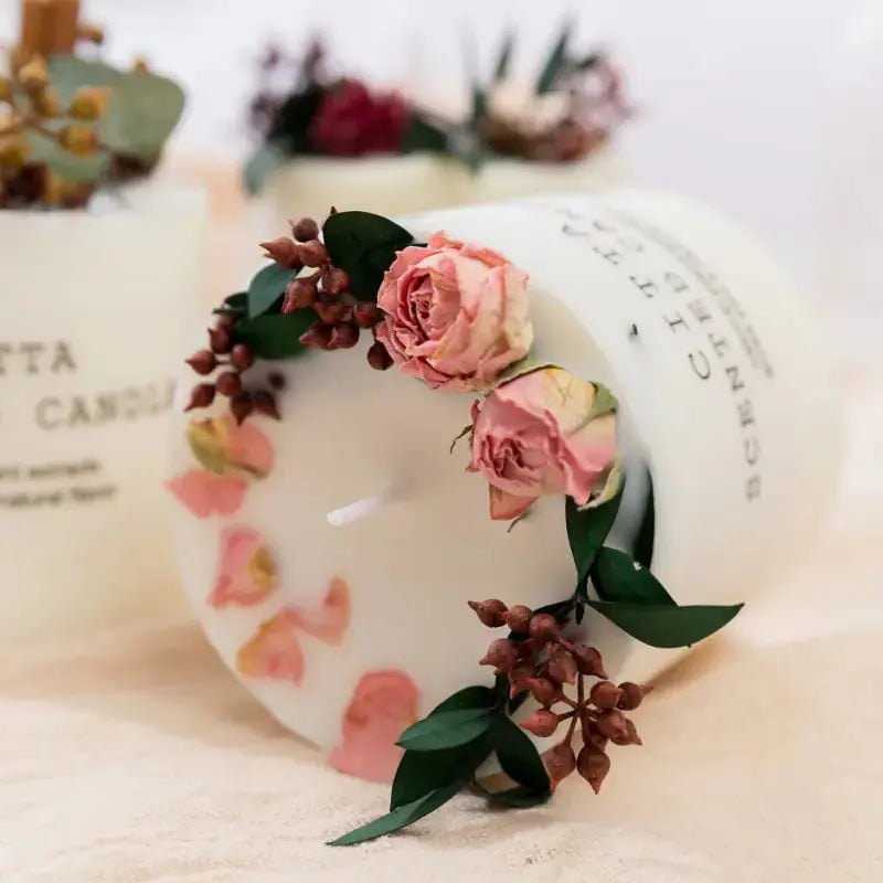 Close-up of a Creative Soy Wax Romantic Aromatherapy Candle by Zendrop, adorned with pink dried roses and greenery.