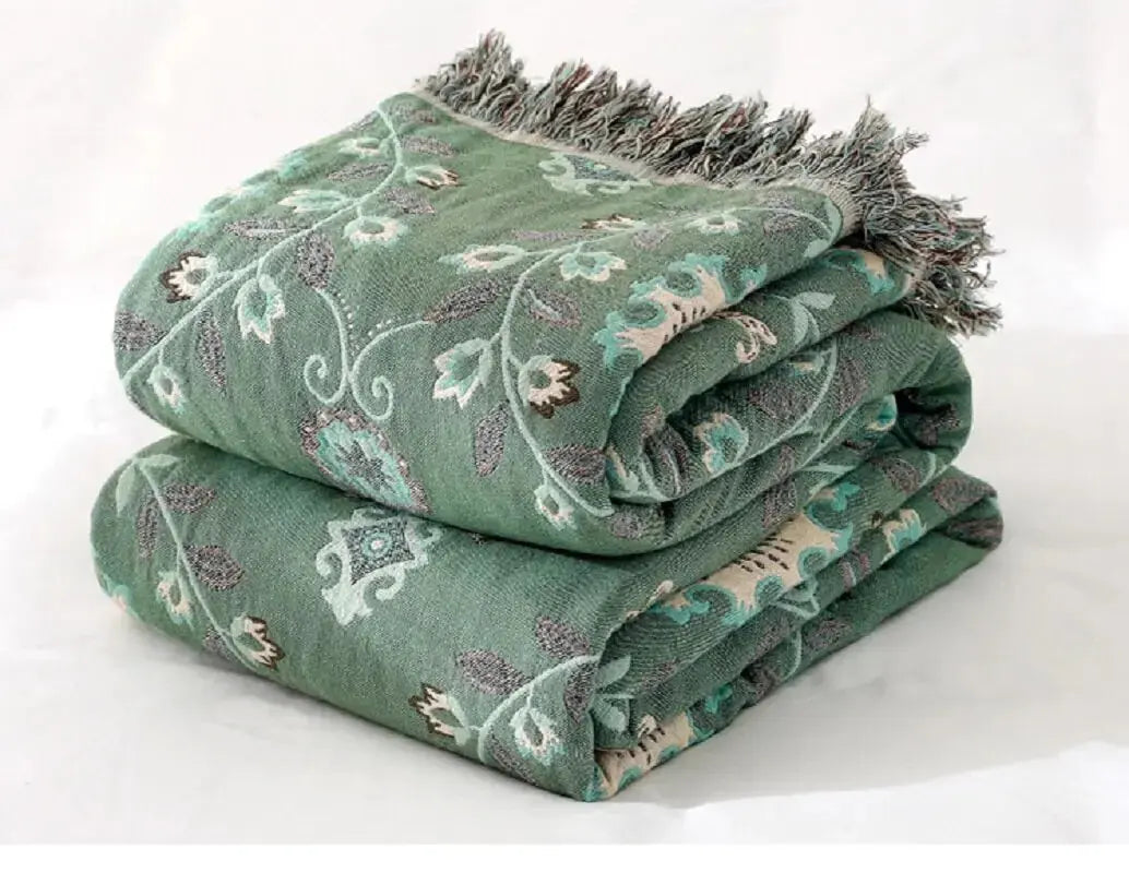 Folded Cotton Sofa Throw Blanket by Zendrop showcasing rich green hues and decorative fringe, ideal for adding comfort and elegance to your home decor.