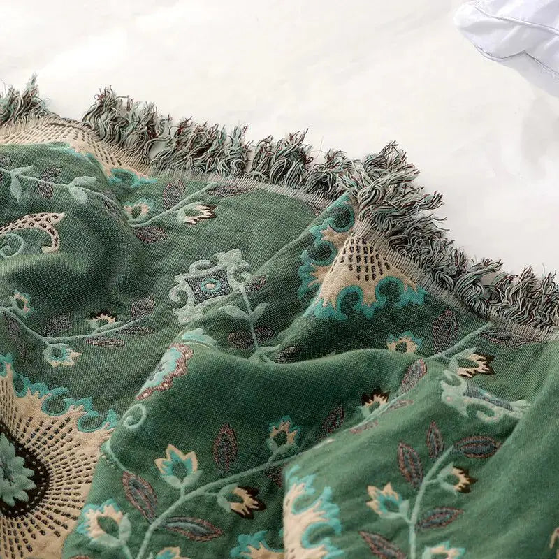Close-up view of the Cotton Sofa Throw Blanket by Zendrop, highlighting the detailing and texture of the green floral fabric with subtle fringe.