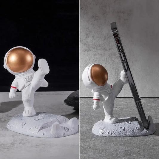 LuxeOrbit Astronaut Phone Holder by Zendrop showcasing a gold and white astronaut design on a textured lunar surface, designed to securely hold smartphones.
