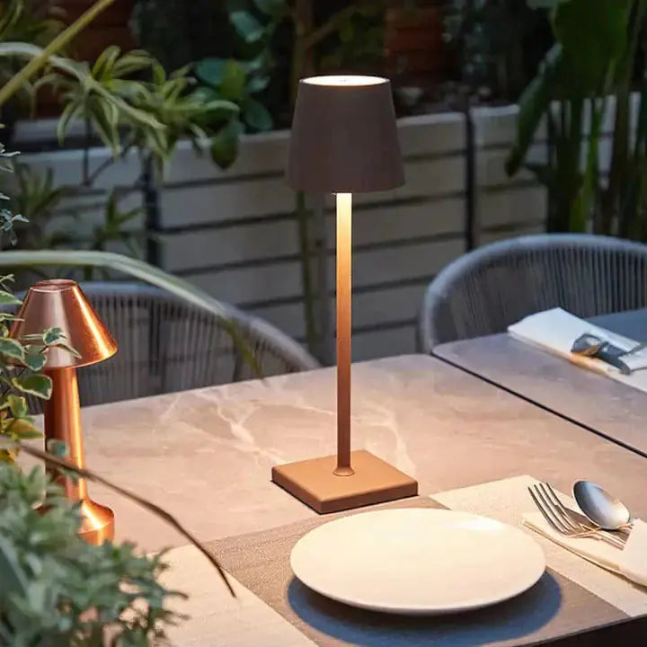 Elegant cordless lamp by Zendrop illuminating a dining table outdoors, surrounded by greenery, creating a warm ambiance.